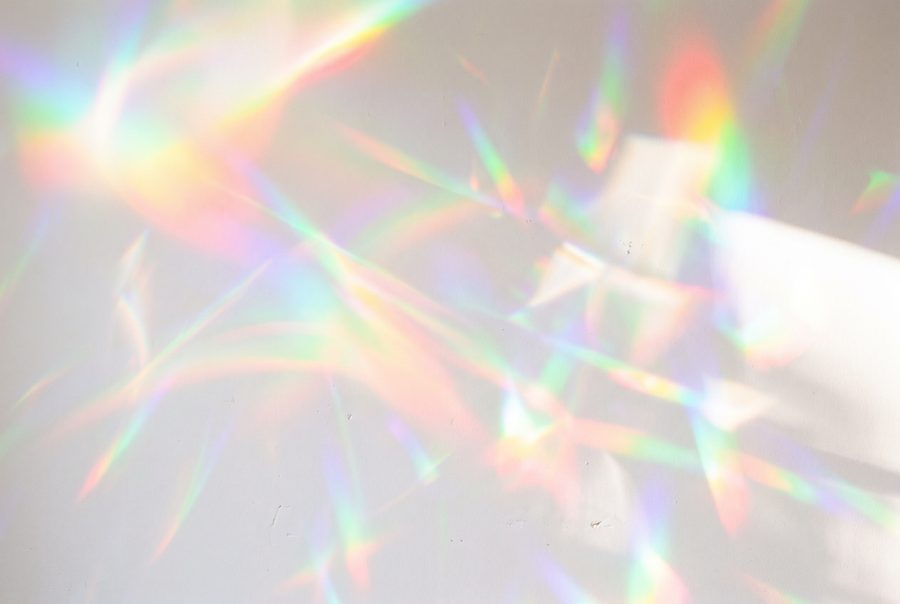 Rainbow prism light leak reflections on white wall, abstract background