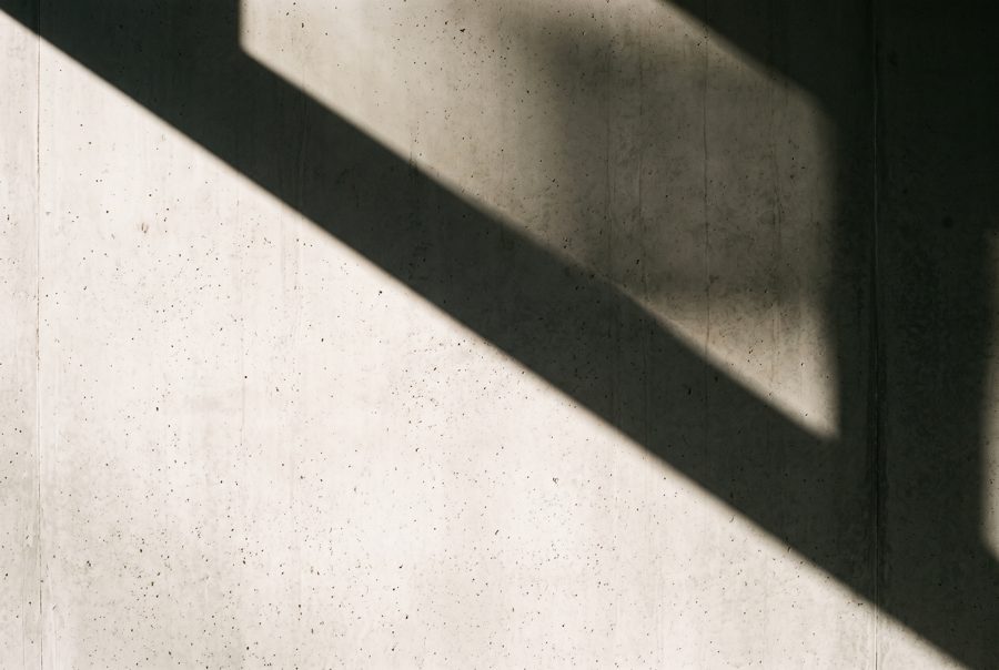 Light gray concrete wall with diagonal sunlight shadow, minimal abstract background