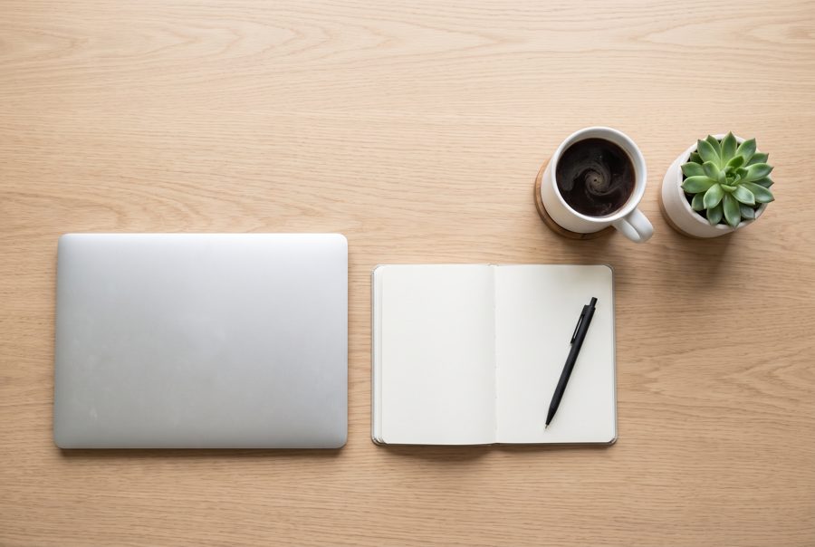 Minimal office desk top view with laptop, coffee, notebook and succulent on light oak
