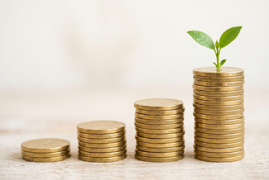 Stacked coins with green sprout, savings and investment growth concept