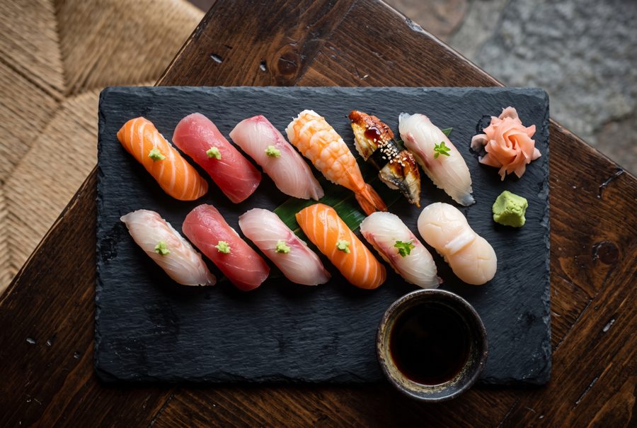 Assorted nigiri sushi platter on black slate with ginger and wasabi, top view