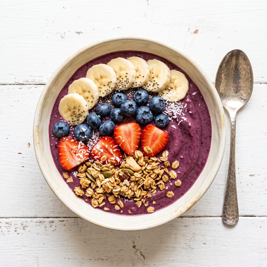 Acai smoothie bowl with banana, berries and granola, top view